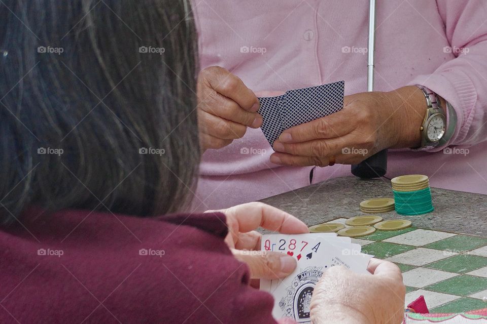 Two people playing five card poker with gambling chips on a permanent concrete checker table in a Chinatown park,, Manhattan, , New York City.
