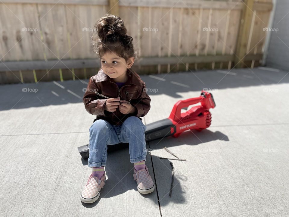 Toddler takes a break while helping mother with yard work, toddler girl sits down on leaf blower, helping mommy with outdoor chores, cleaning up outside with a toddler, toddler helps mommy