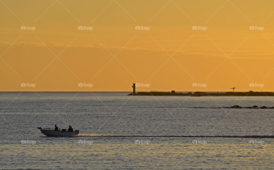 People travelling in boat at sunset