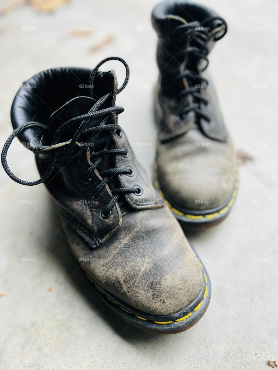 Overhead closeup of thirty year old classic Doc Martens boots on a cement floor with autumn leaves. Symbol of workmanship and lasting quality. @9bachelors Instagram