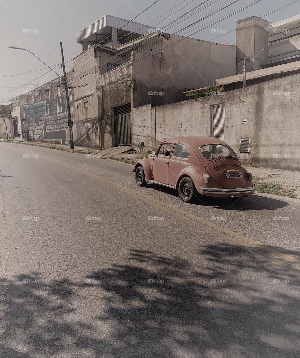 A classic Beetle on a quiet street, evoking nostalgia with a vintage touch. The worn urban setting complements the car's rustic charm.