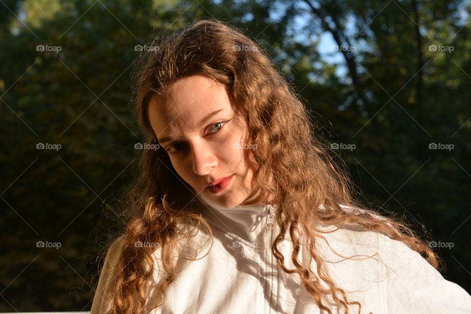 brunette girl beautiful portrait in sunlight outdoor green background