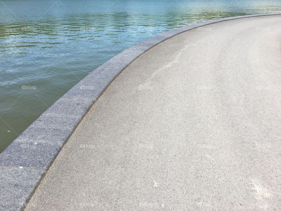 Curvy path along green blue water with ripples and reflections 