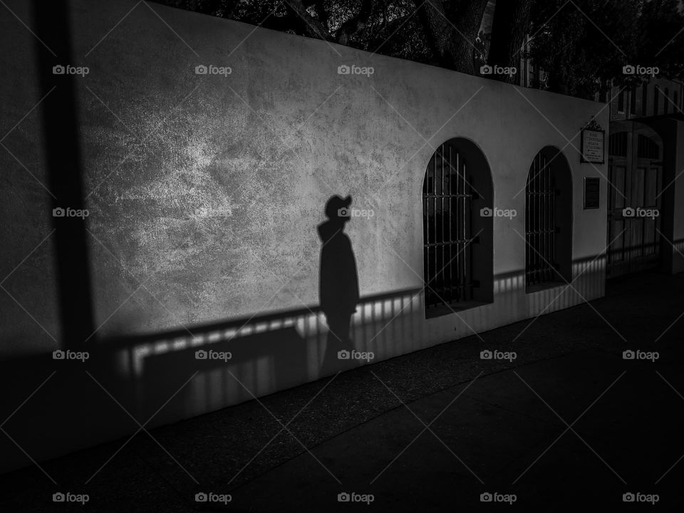 Shadows in black and white; A mystery man waking outside the exterior walls of a Spanish courtyard.