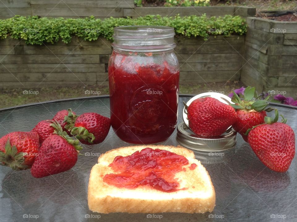 Homemade strawberry jam with a slice of toast smothered with jam.