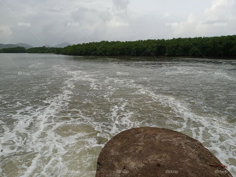 Beautiful view of the river in middle of the half round bridge pillar it's looking nice with nice background of mountain and clouds