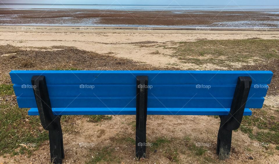 Blue bench on remote beach at low tide seascape landscape 