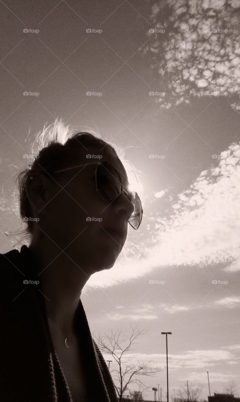 black and white silhouetted woman in sunglasses under sky with clouds