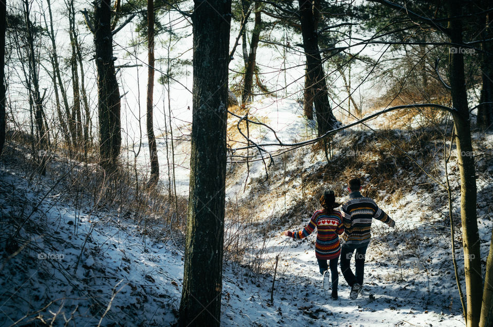 Couple holding hands run away to the forest in winter
