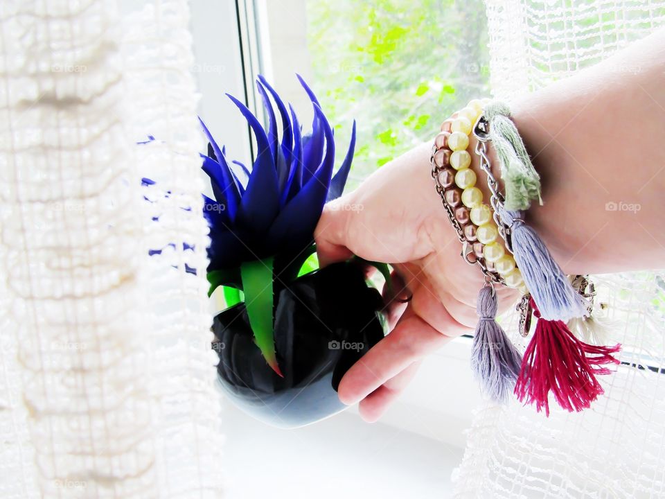 Handmade bracelets on the arm with a flower pot in her hand