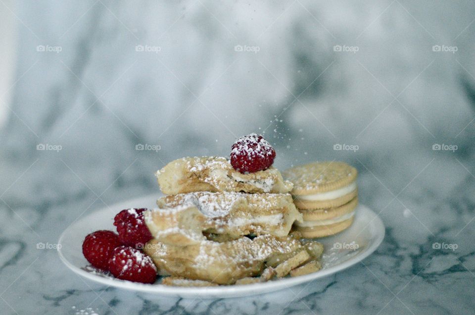 Golden double stuff Oreo cookies and a waffle with raspberries and powdered sugar