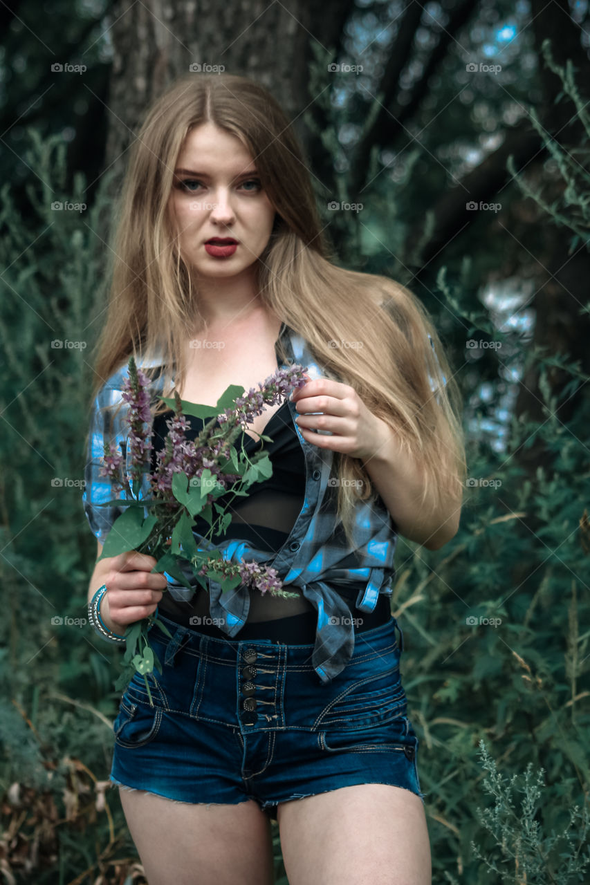 A girl with blond hair in a plaid shirt and short denim shorts on a background of trees and nature,
Girl, woman, man, people, blonde, blonde hair, checkered shirt, shorts shorts, denim shorts, forest, nature, trees, grass, feelings, emotions, tenderness, love, lifestyle, lifestyle, recreation