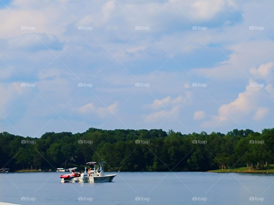 Wildlife boat pulling over and searching a boat on the lake.
