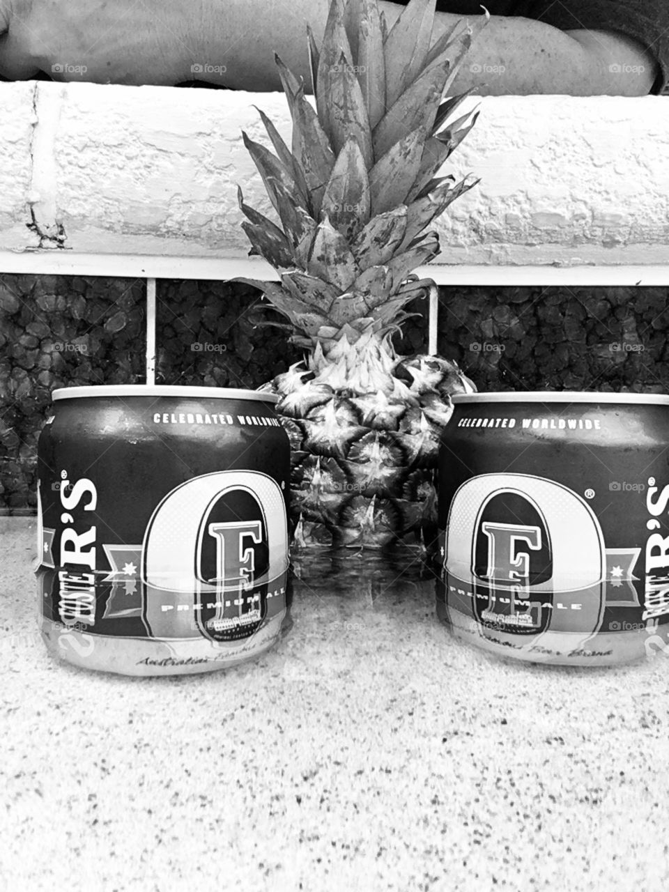Black and white Fosters beers with pineapple in water poolside 