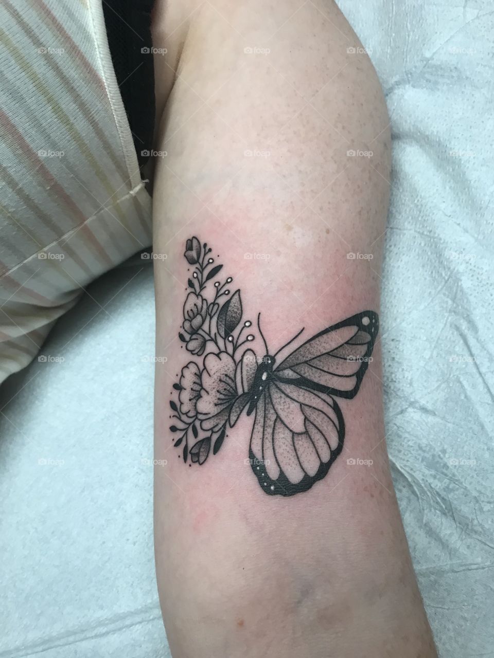 Freshly inked arm tattoo of a butterfly and flowers all over the place
