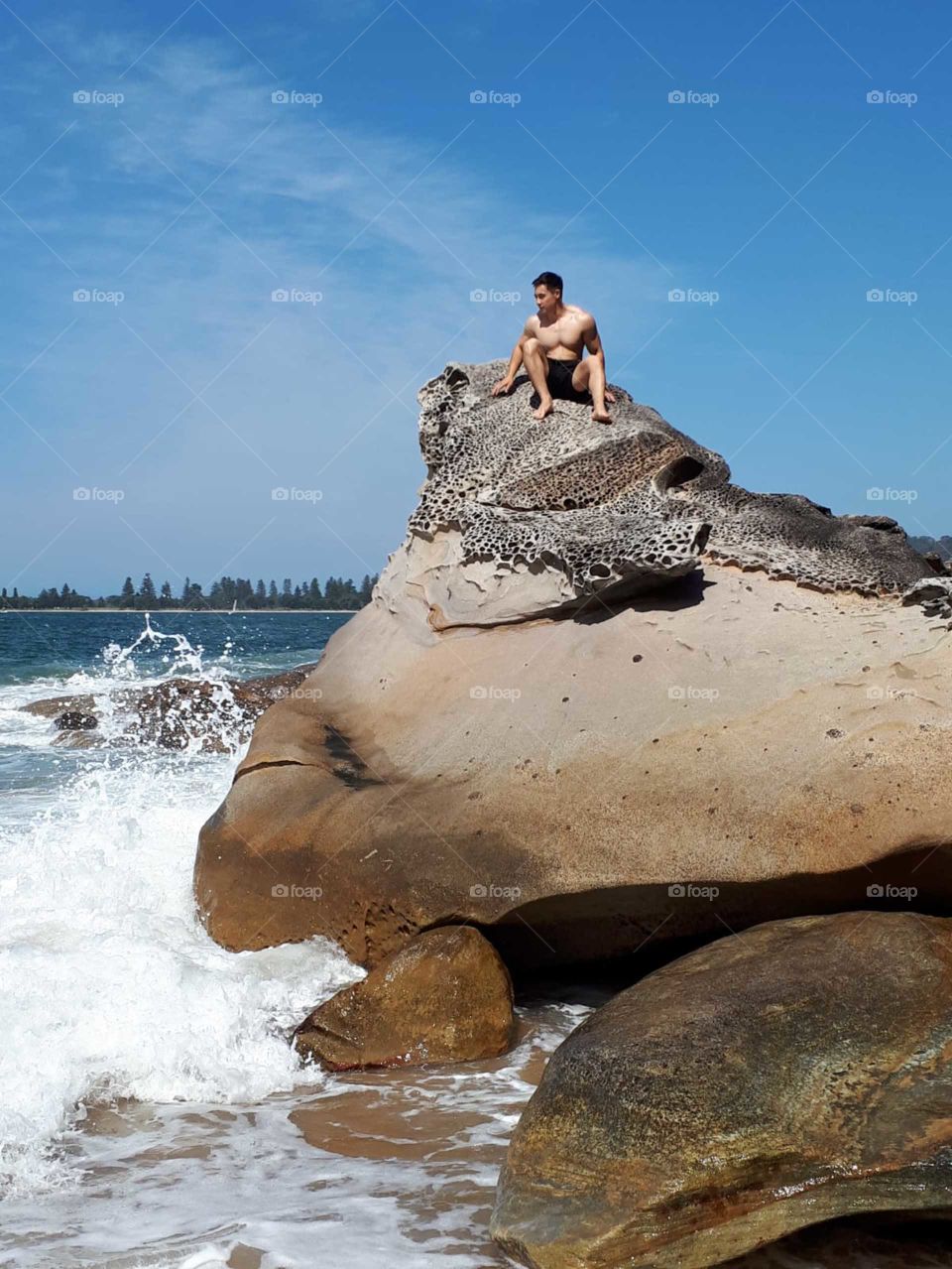 Man sat on a rock at Curl Curl beach Australia 