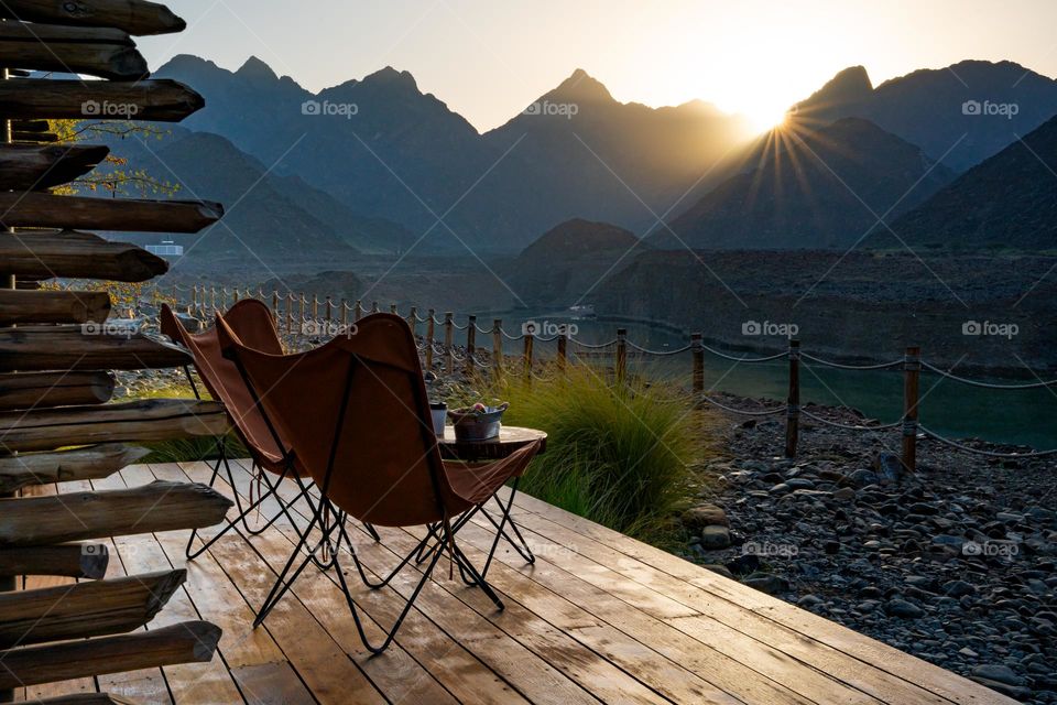 Idyllic sunrise view in the mountains. Glamping in mountains. Two chairs on wooden terrace