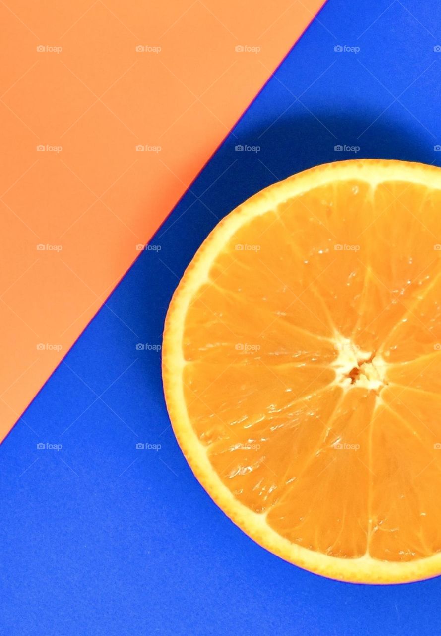 Juicy orange slice on blue and orange paper