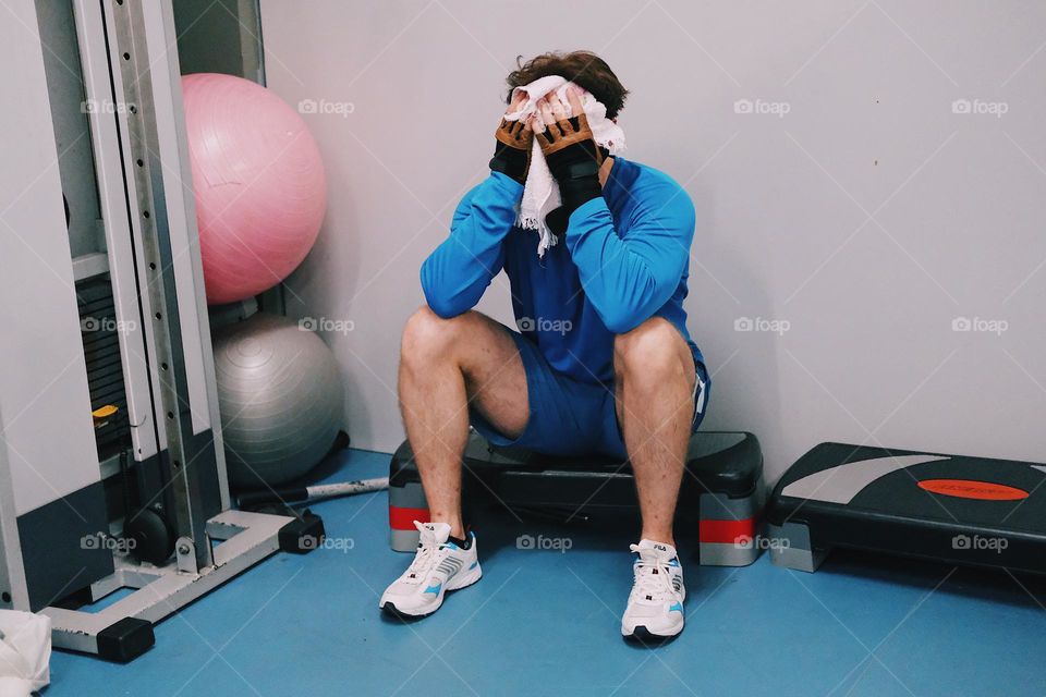 A man in a sports uniform wipes his face after a grueling workout in the gym