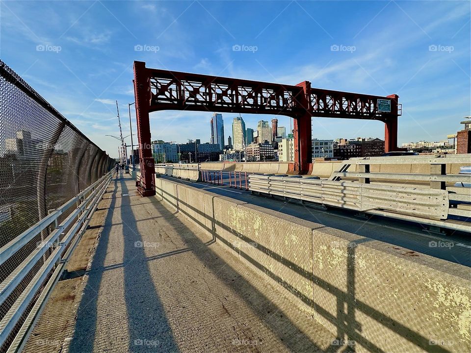 This is the “Pulaski Bridge“ at „Newtown Creek“ that connects „Greenpoint“, Bklyn to LIC, Queens in the warm light of the evening sun. Dramatic shadows on the pedestrian lane accentuate the streamlined shapes in the design. 2024. Hypnotic Productions