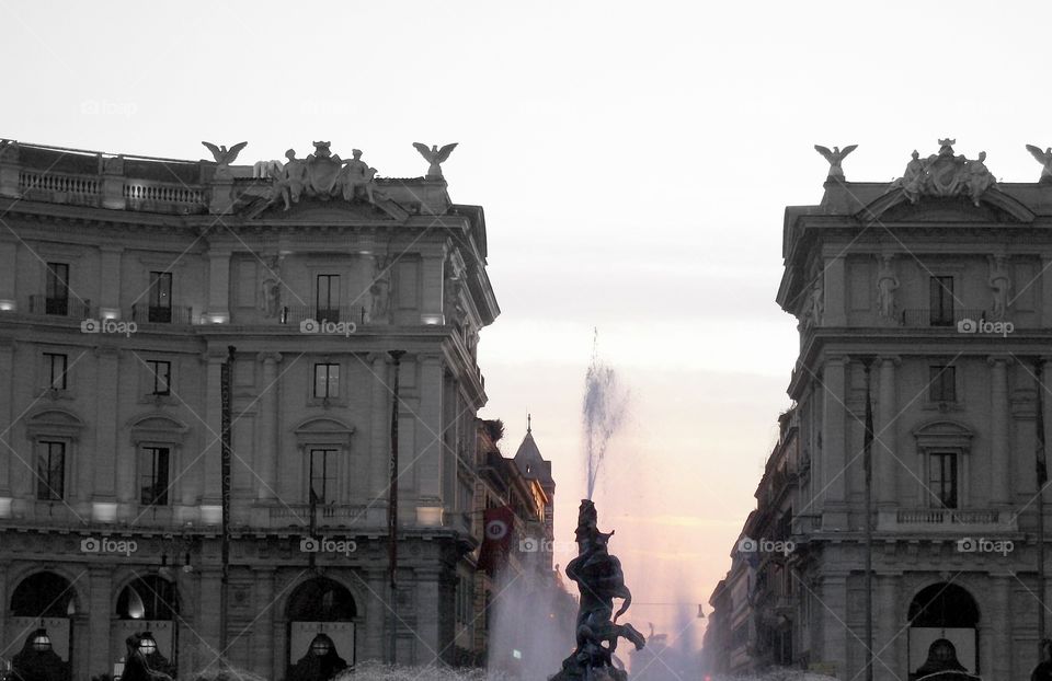 A fountain spraying high as dusk falls over this Italian piazza
