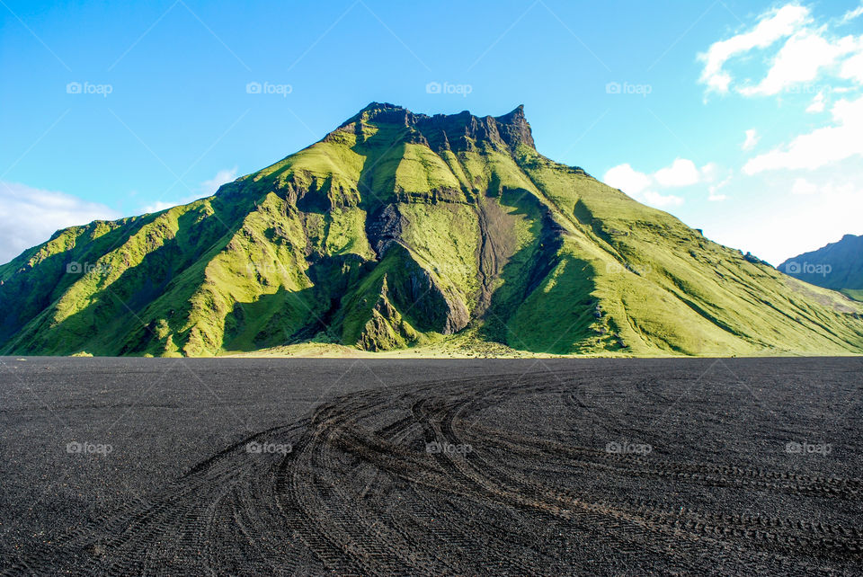 An Icelandic Mountain surrounded by a black sand desert.