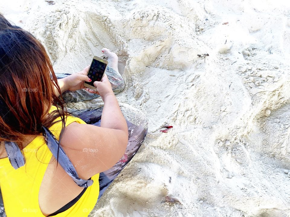 A woman using phone at the beach