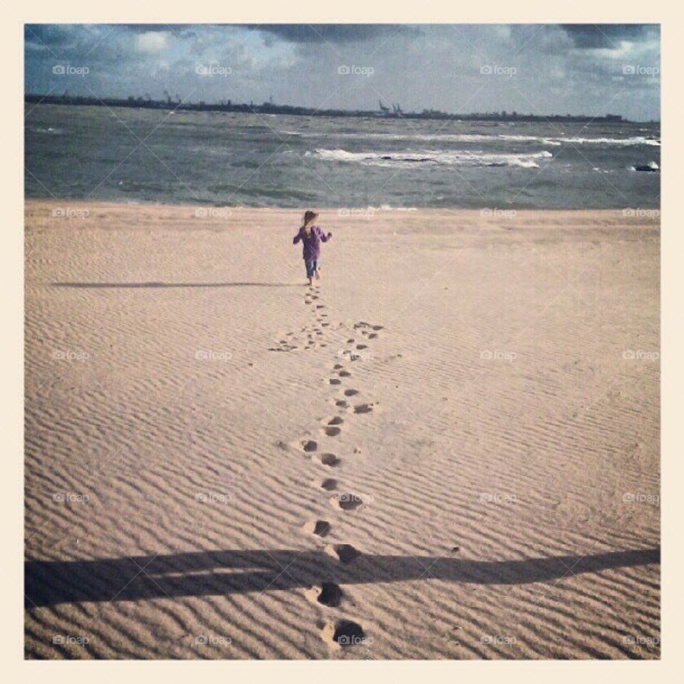 Little girl leaving footprints on the beach 