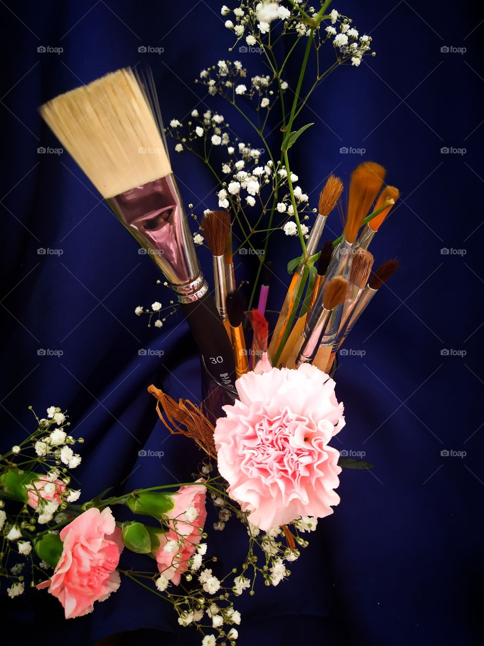 Bouquet of brushes for painting on a background of pink carnations