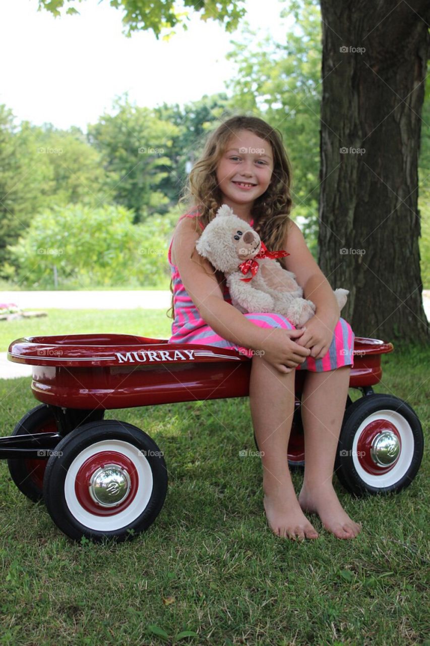 Smiling girl sitting on wheel barrow