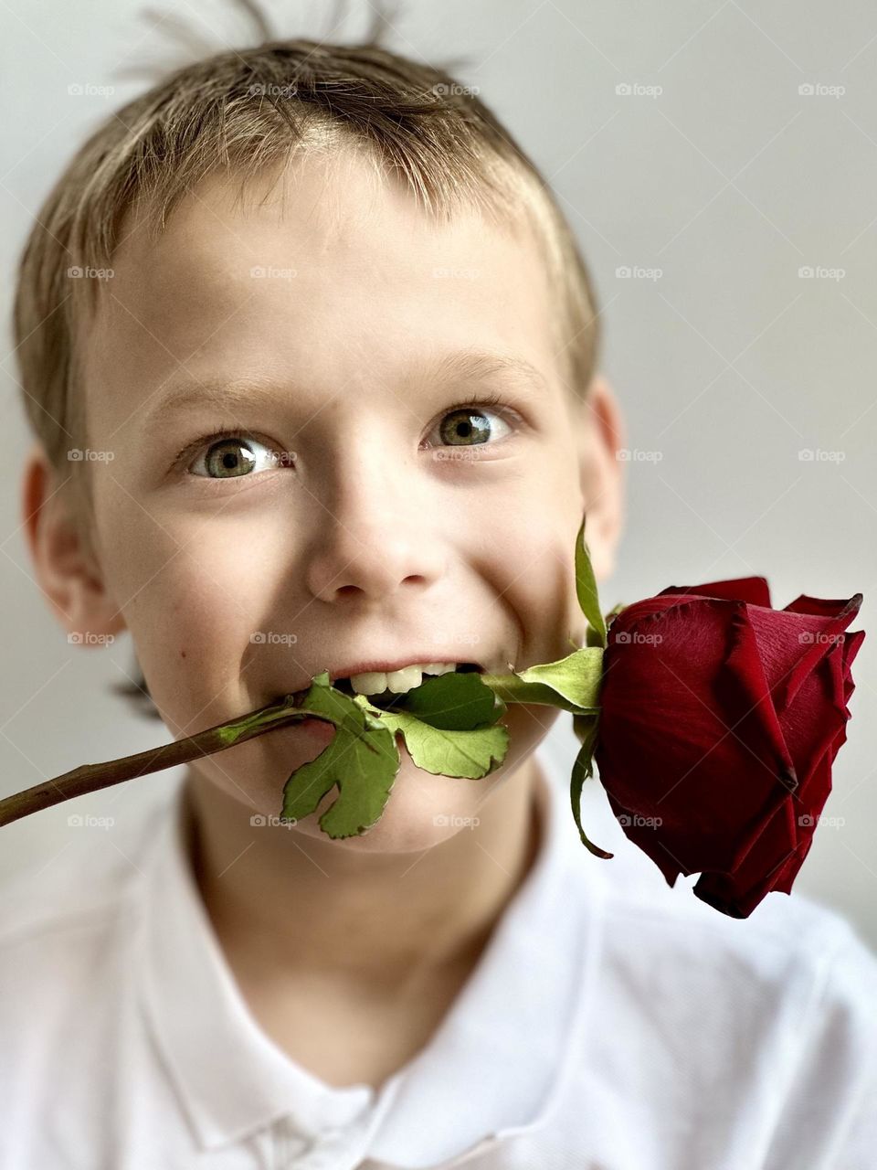 smiling boy with a rose in his mouth