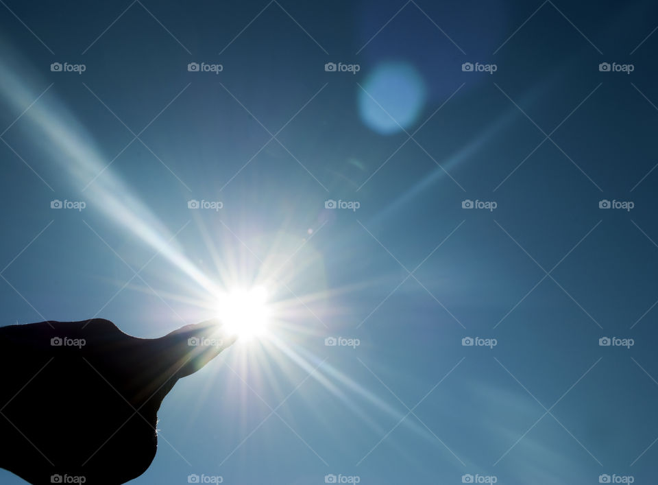 Finger pointing at the sun rays