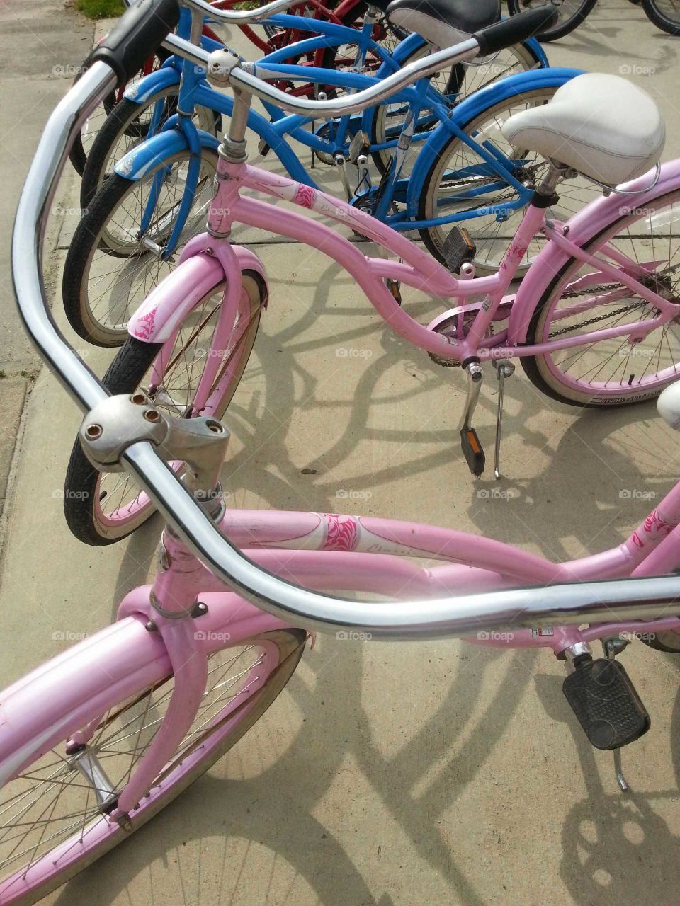 Rental bicycles lined up on a sunny day waiting to get used.