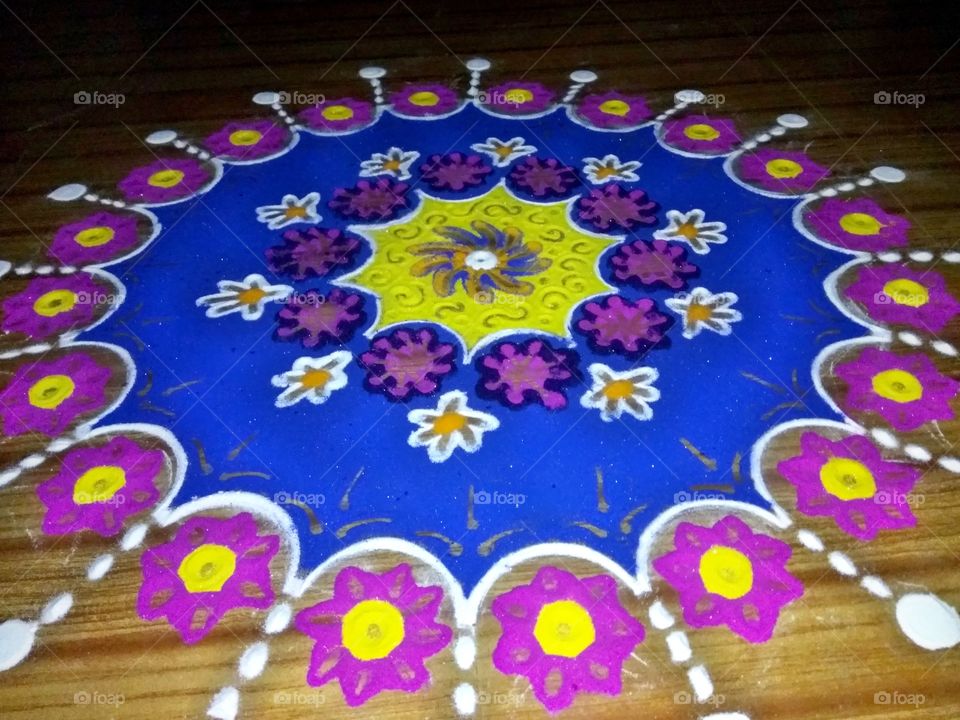 Rangoli is an art, origin in India in which patterns are created on the floor in living rooms or courtyards using materials such as colored rice, dry flour, colored sand or flower petals. It is usually made during Diwali or Tihar (collectively known as Deepawali), Designs are passed from one generation to the next, keeping both the art form and the tradition alive.

The purpose of rangoli is decoration, and it is thought to bring good luck. Design depictions may also vary as they reflect traditions, folklore and practices that are unique to each area.
