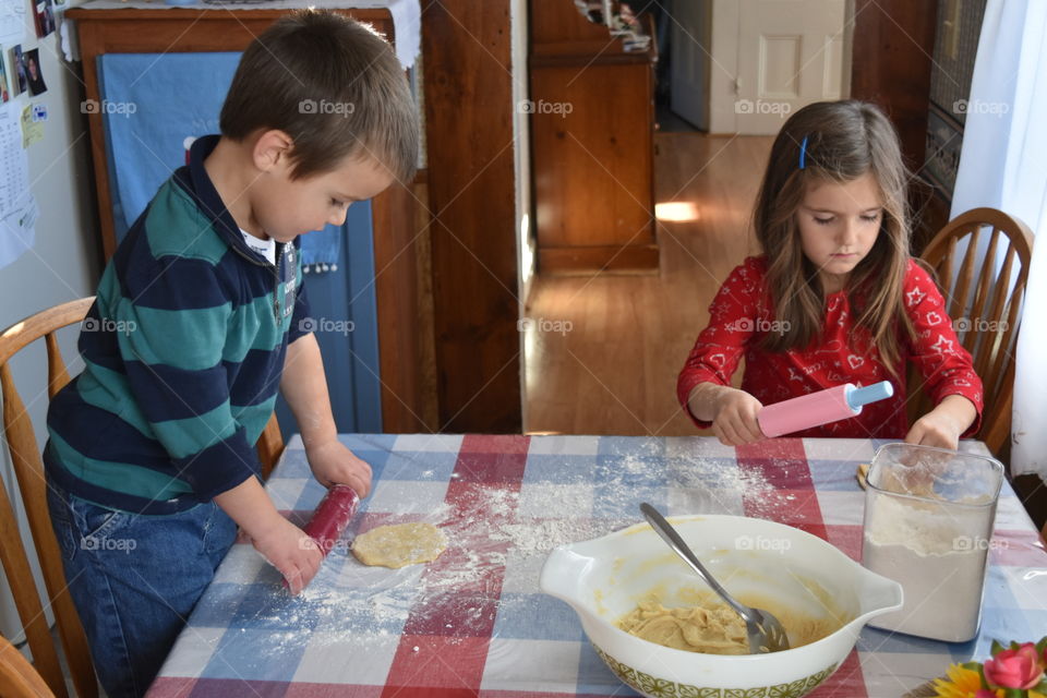 siblings rolling out dough