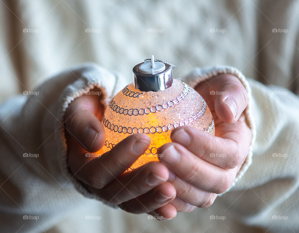 Close-up of woman hands holding Christmas light bauble.