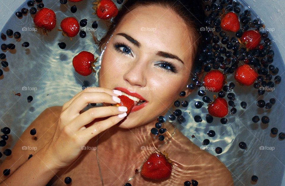 Woman in bathtub eating strawberry