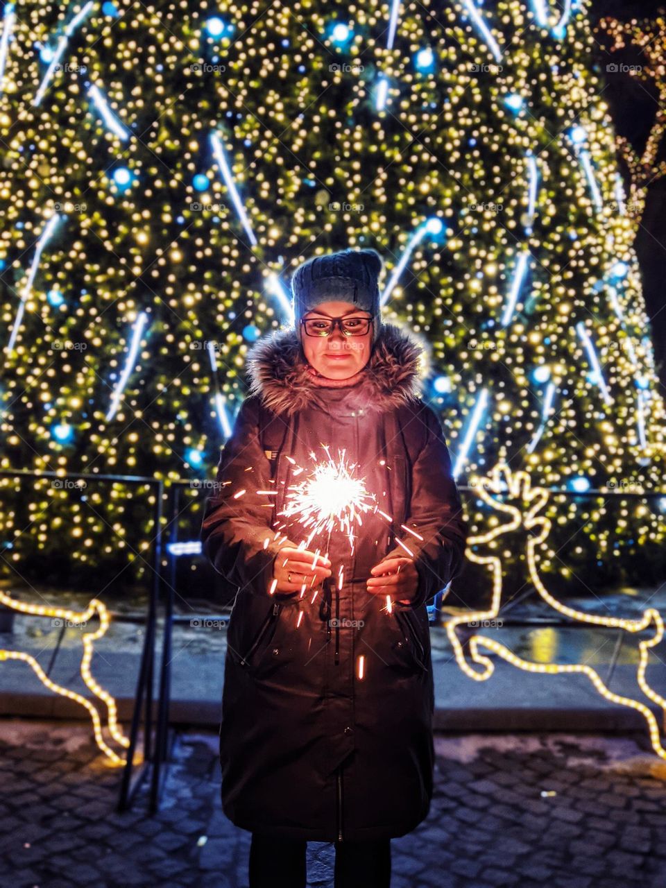 Portrait of young happy, beautiful woman in eye glasses in Christmas,  New Year city with illumination and garlands