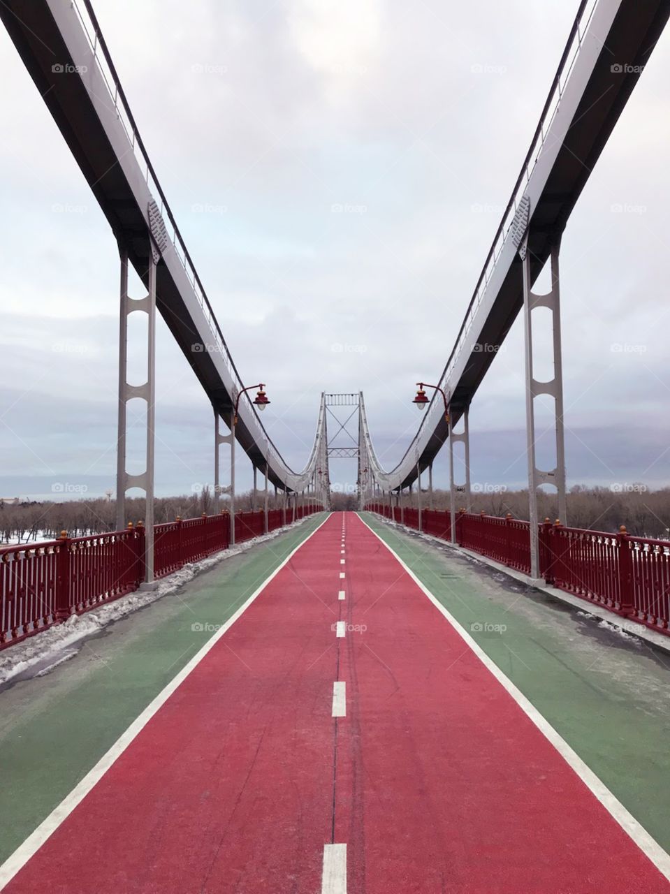 Perspective view of green and red pedestrian bridge across Dnipro river in Kyiv, Ukraine 