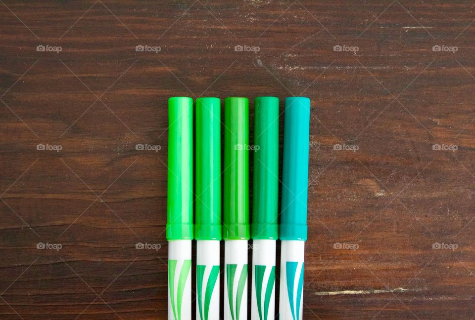 Green Color Story - green markers on a dark wooden surface 