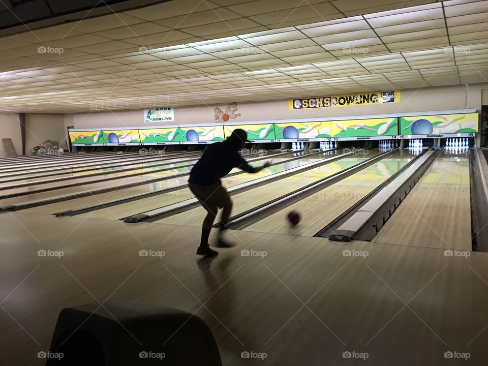 Dark silhouette bowling in bowling alley
