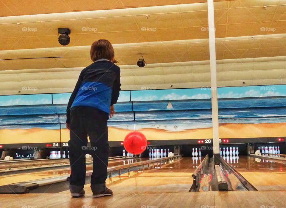 Boy At A Bowling Alley. Boy Enjoying A Classic American Pastime
