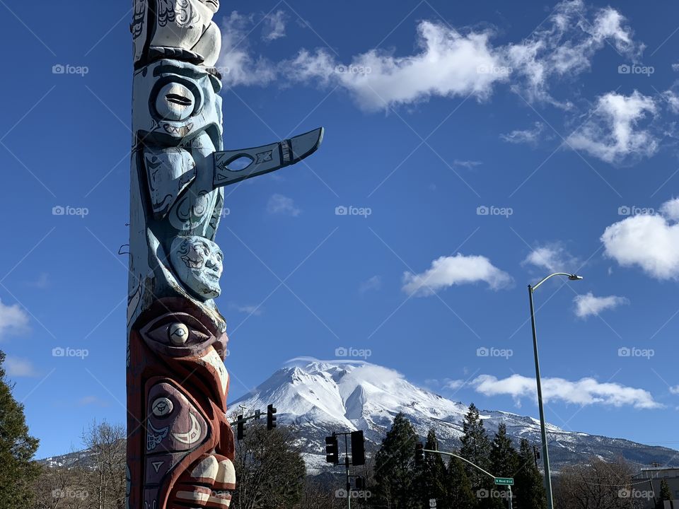 Blue skies, Snow White Mt Shasta with a totem pole stretching into the sky