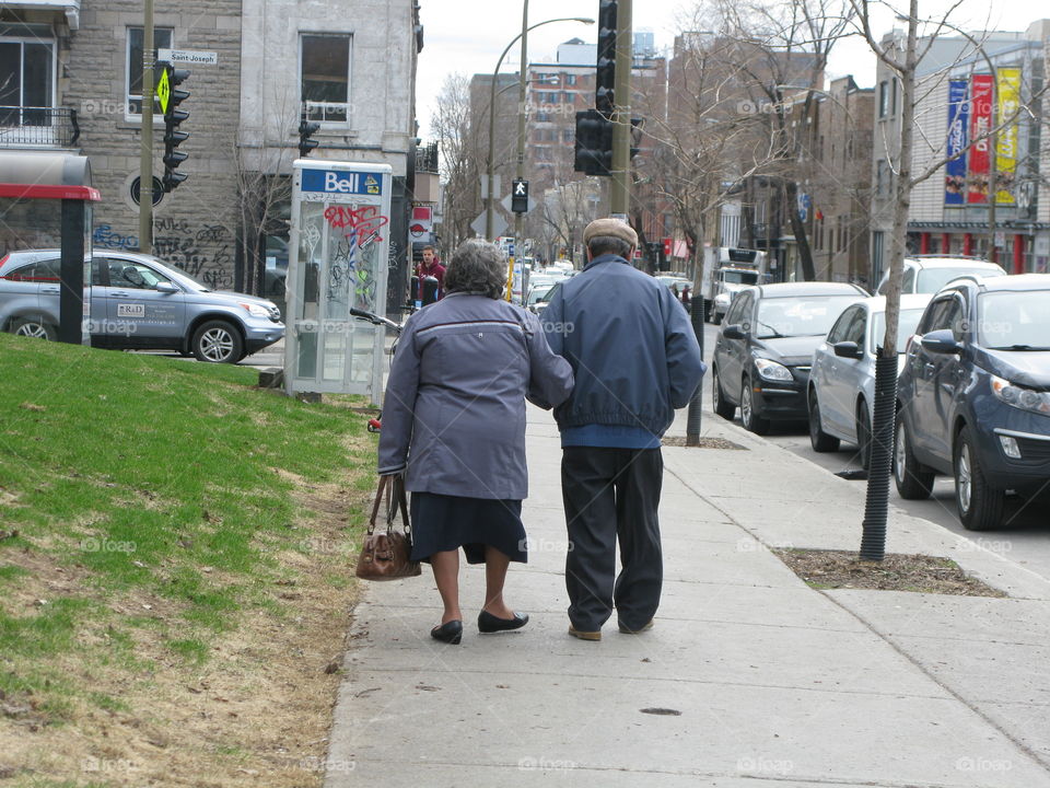 A elderly couple walking arm in arm