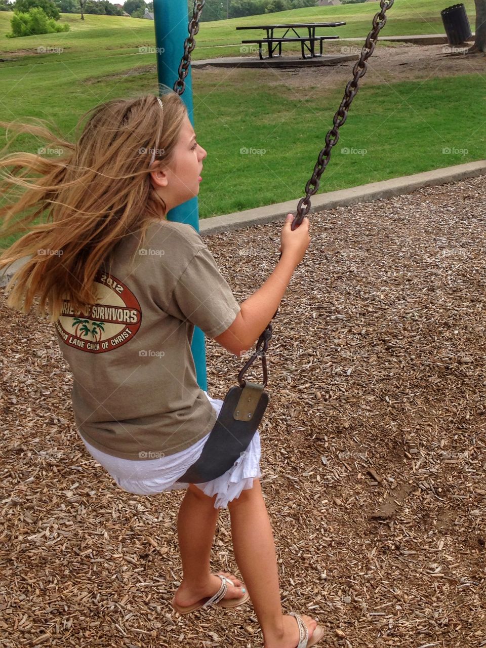 Swing with the wind. Girl swinging at the park