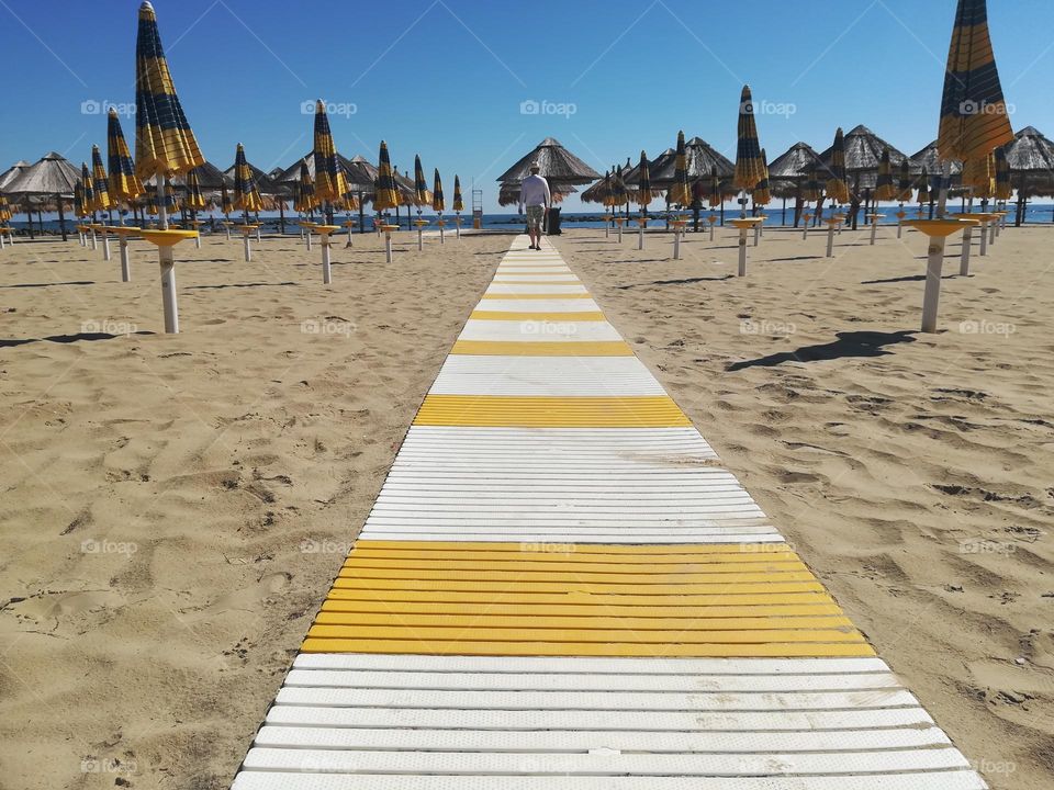 man in the distance walks on the boardwalk at the beach