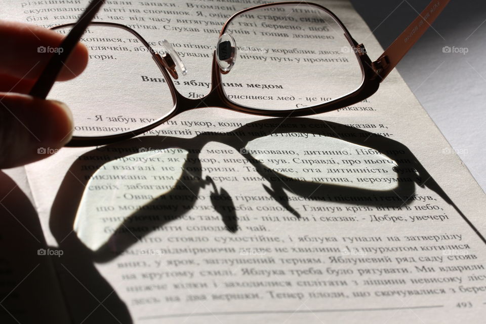 Reading glasses throwing a butterly- shaped shadow on a book