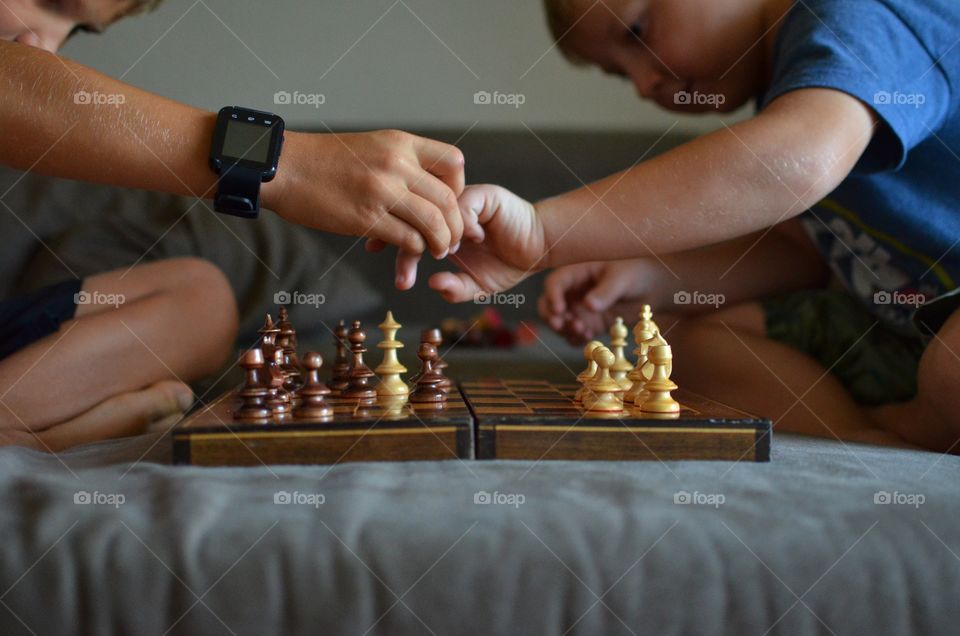 The big brother teaches the little brother how to play chess. It is pretty intense. He tries to persuade the learner not to make a move. 