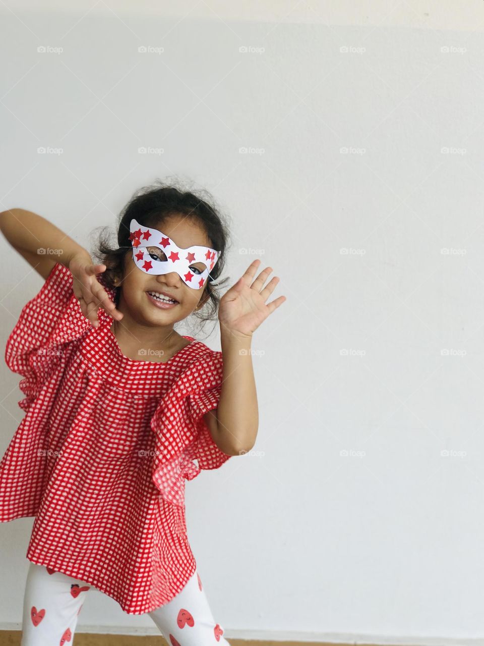 A cute girl dancing with eye mask and wearing red dress.