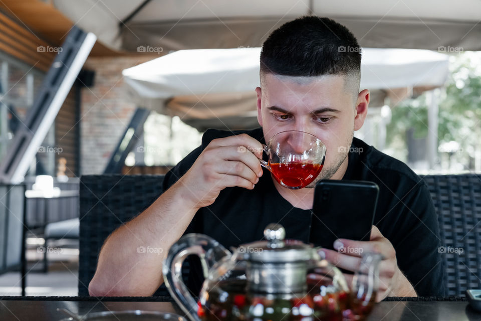 yong man drinks ice berry tea in cafe